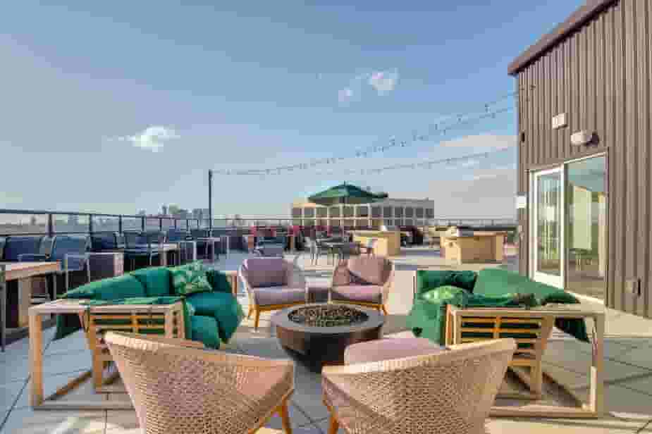 Rooftop Lounge showing fire pit, lounge seating, dining tables, grills, and views of Downtown Minneapolis