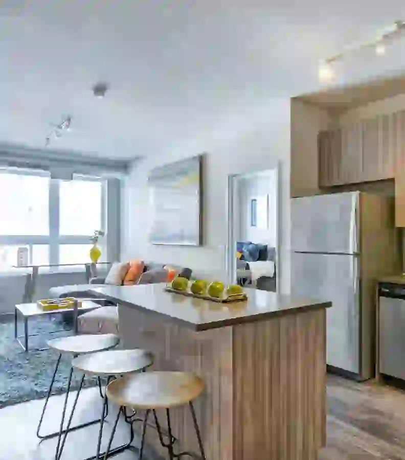 Kitchen island with washed wood look, stainless steel appliances and living area in the background