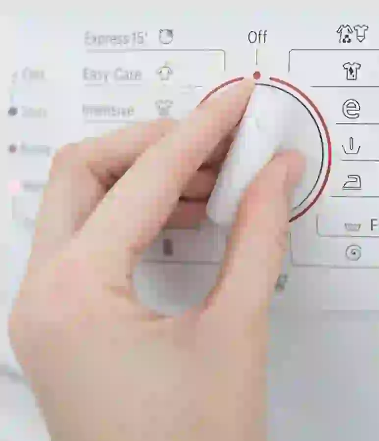 Hand turning a dial on the included washer and dryer